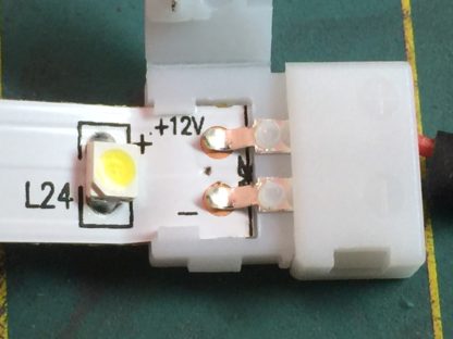 The LED tape inserted into the quick connector. Note how the connector has tabs to hold the LED tape in place straight. You want the tape to be all the way in so the metal contacts on the connector are resting on the contact dots on the tape.
